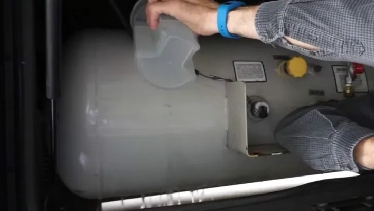Pouring hot water down the side of a propane tank to check propane tank level..