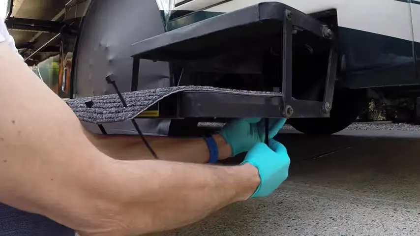 Feeding cable ties through back eyelets of RV step cover