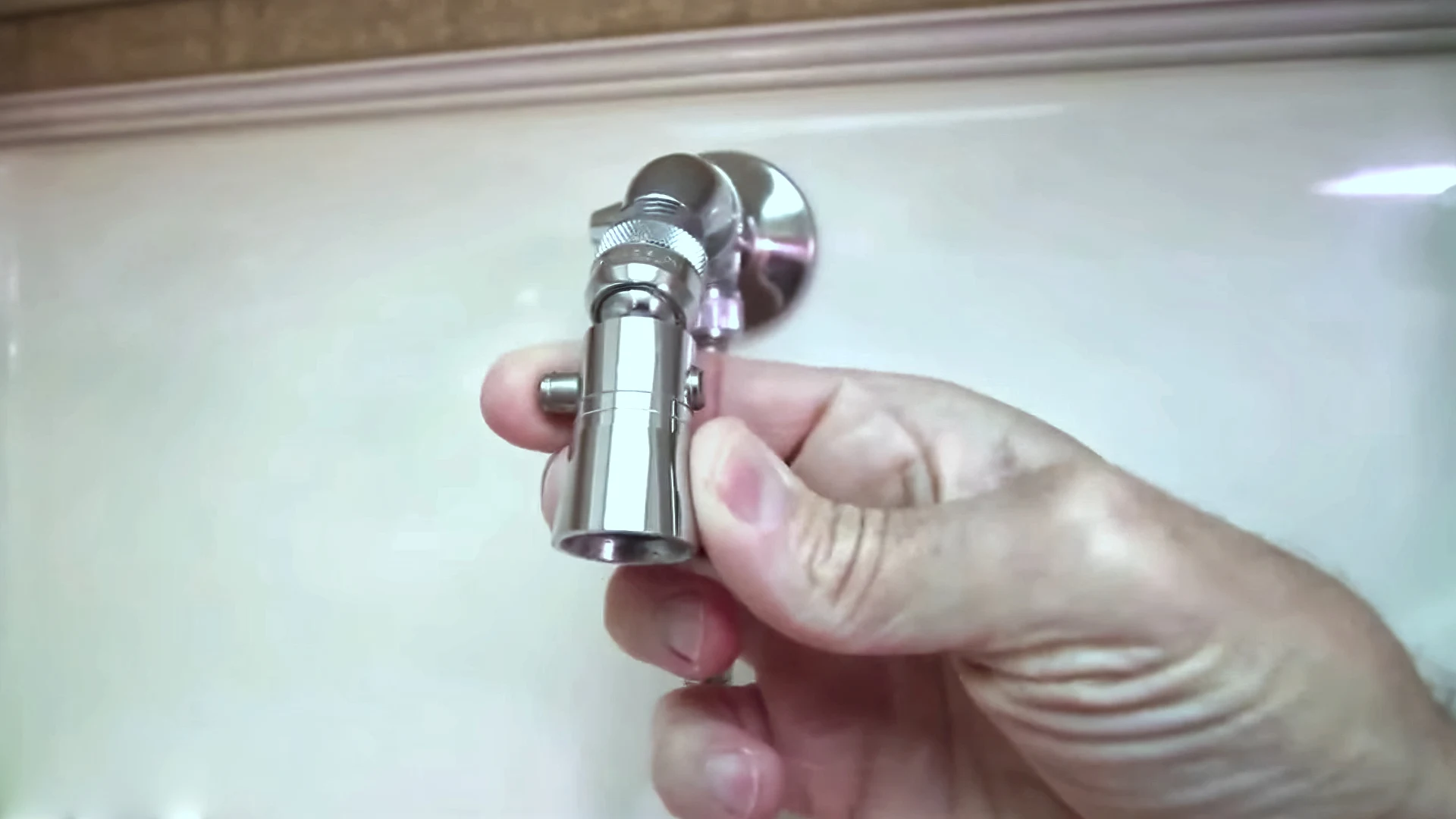 Photo of a hand unscrewing an RV shower head that's clogged to demineralize it