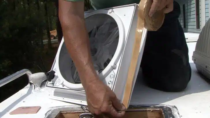 applying butyl tape around the flange of the RV roof vent fan.