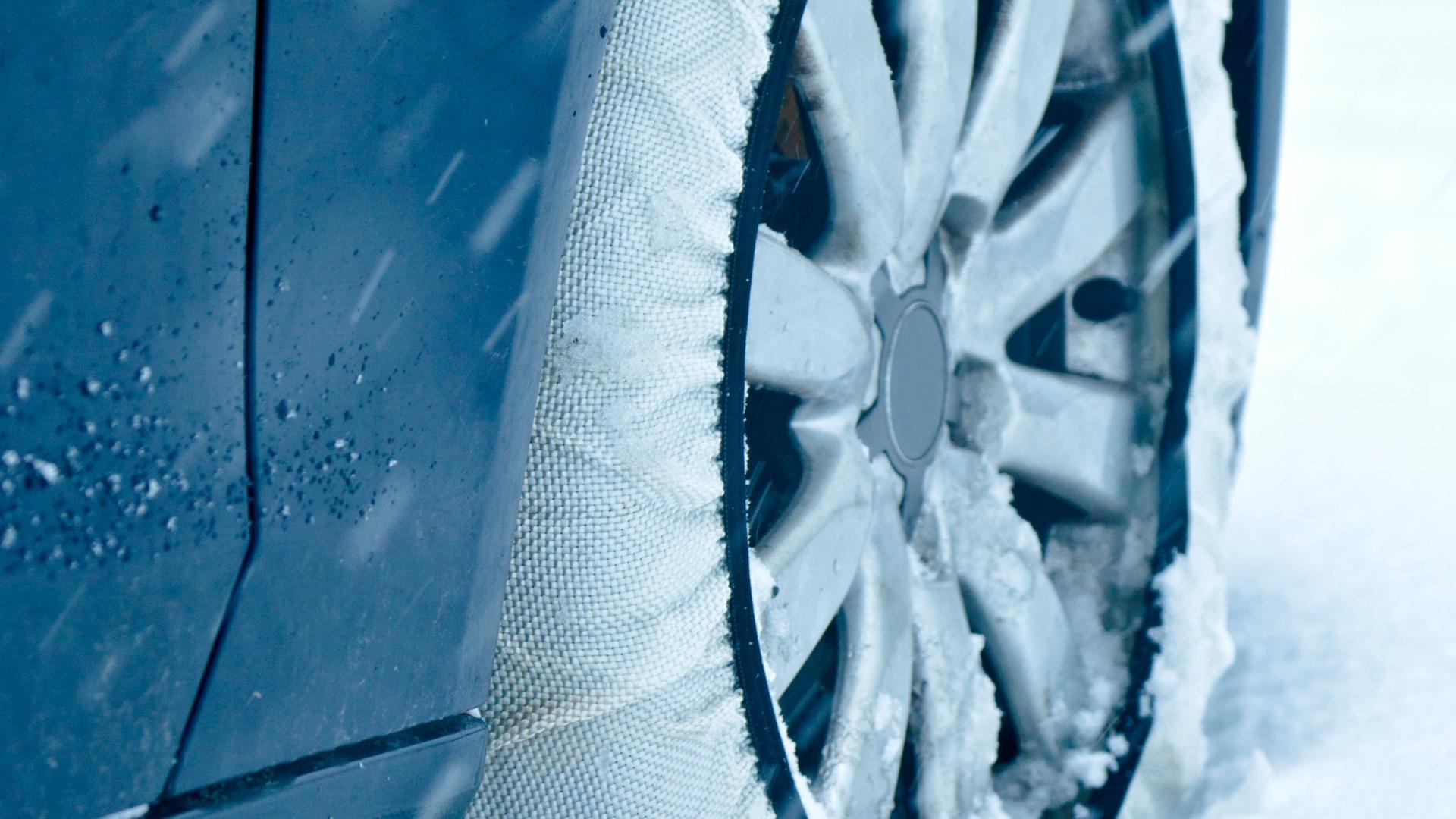 A fabric snow sock vs chains on a tire in snow