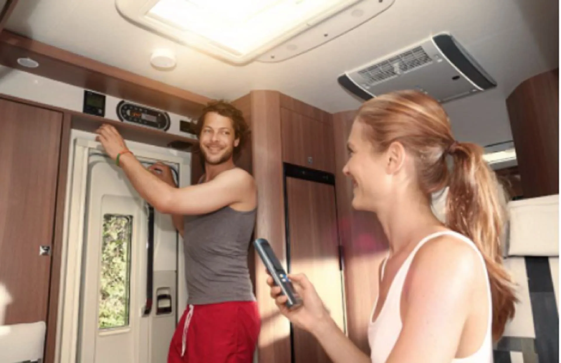 Photo of a Truma AC unit running in a caravan while two people converse.
