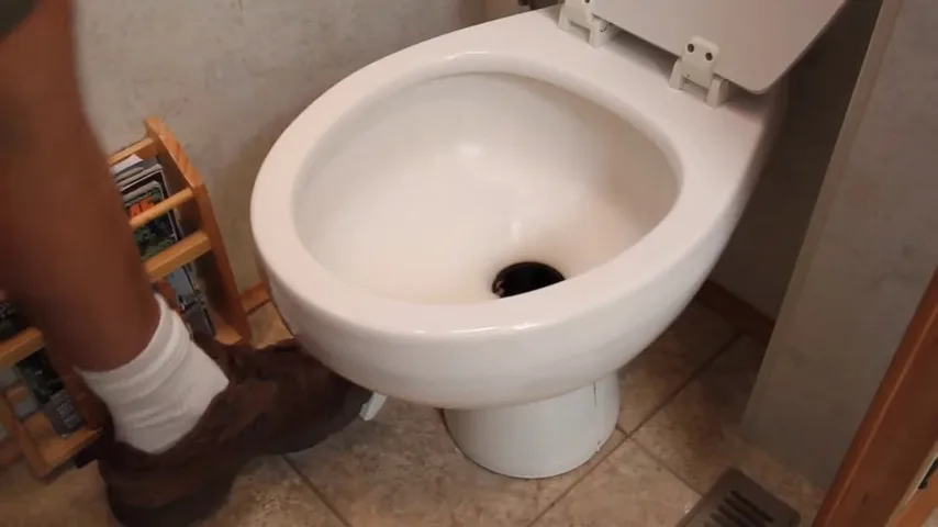 Foot pedal being depressed, releasing water into the RV toilet bowl