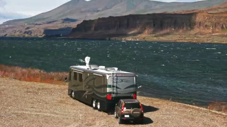 Photo of The RVgeeks' motorhome parked alongside a body of water and the mountains, boondocking - debunking full time RV myths.