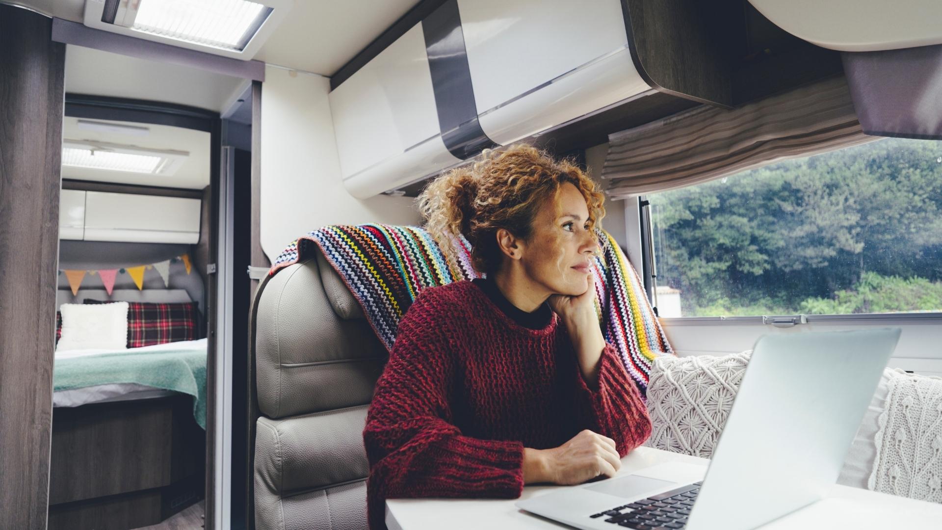 A woman in a sweater inside a mid-sized RV, warm because of her RV propane furnace