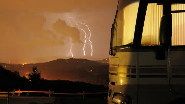 A motorhome with lightning from a storm in the distance