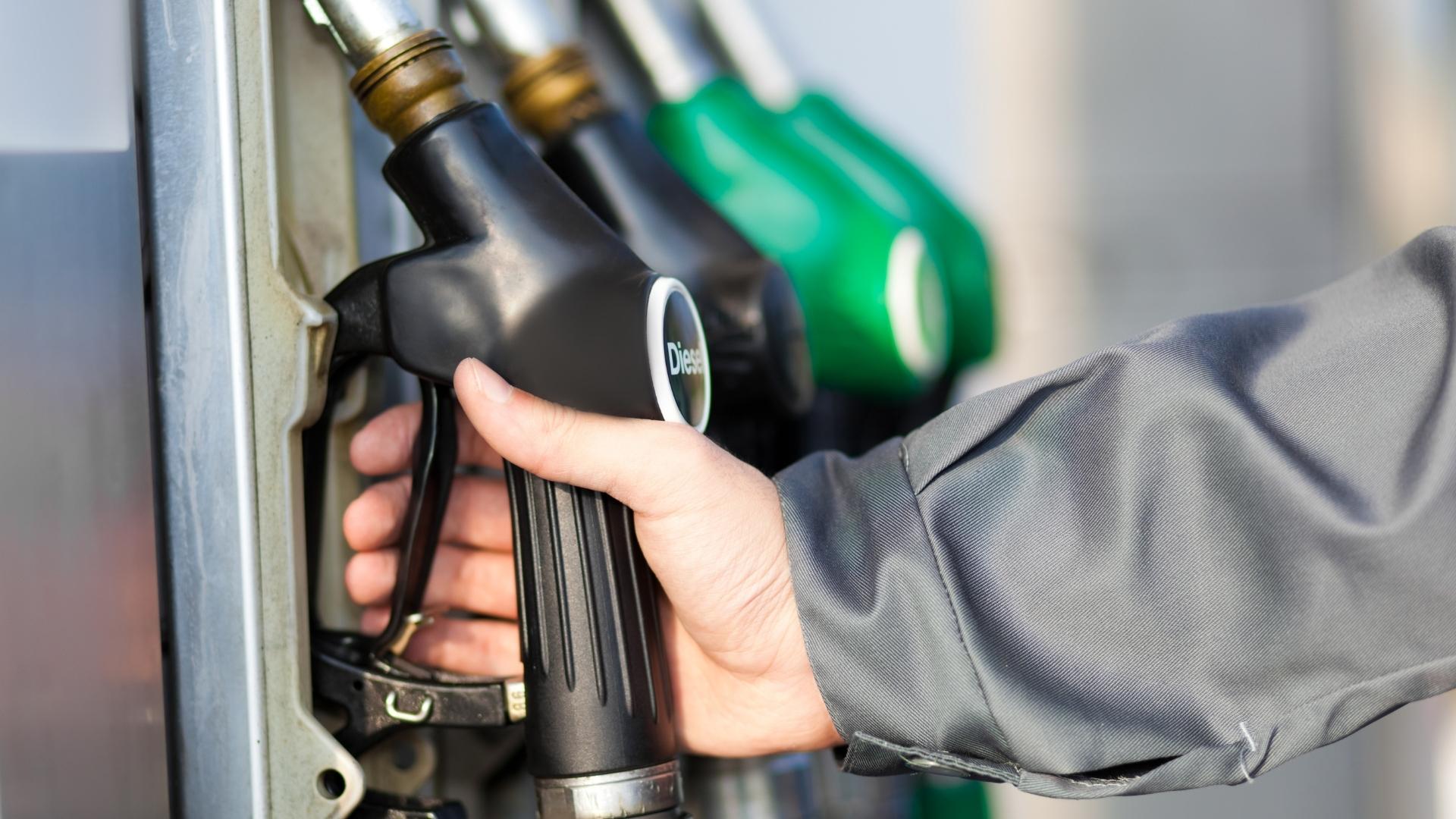 Photo of a hand taking hold of the diesel pump at a fueling station