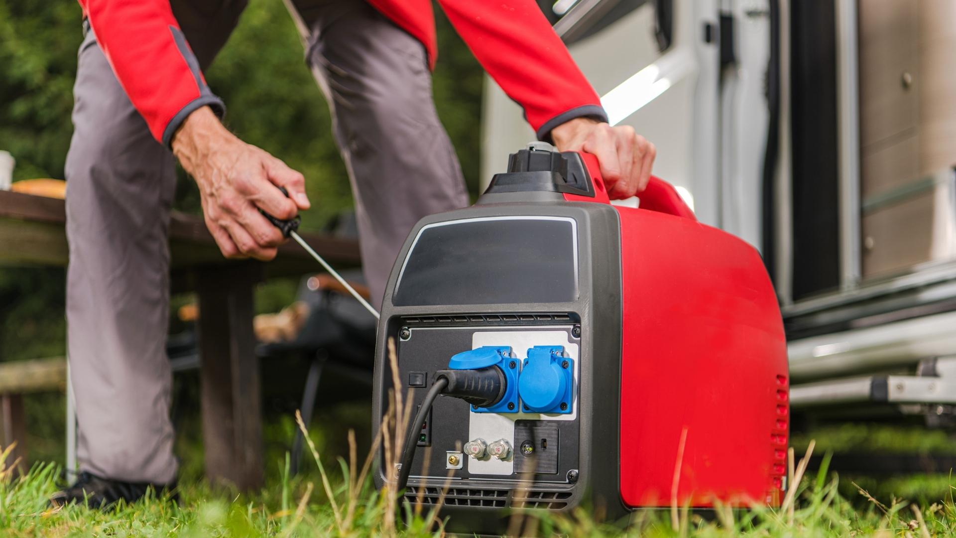 Photo of a person starting a small portable generator very close to an RV