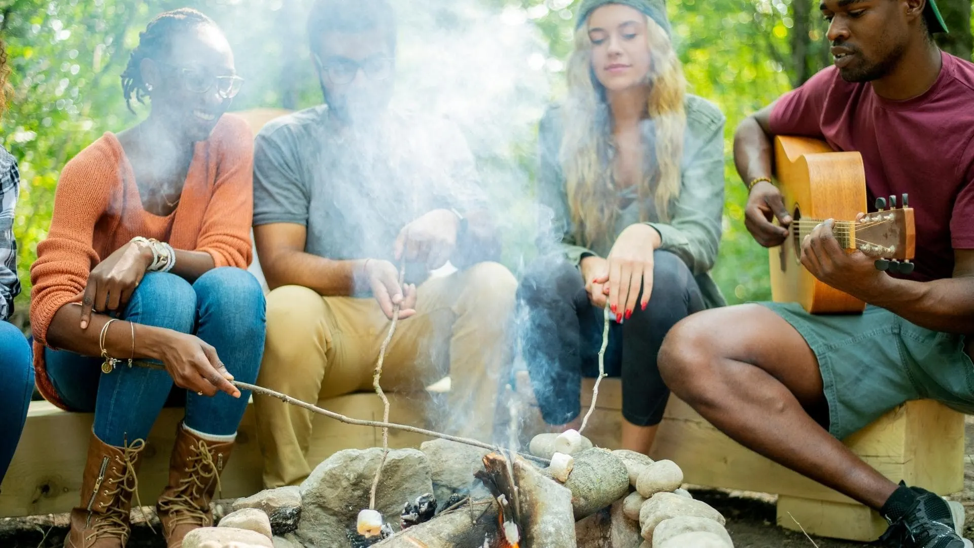Photo of a group of friends gathered around a smoky campfire