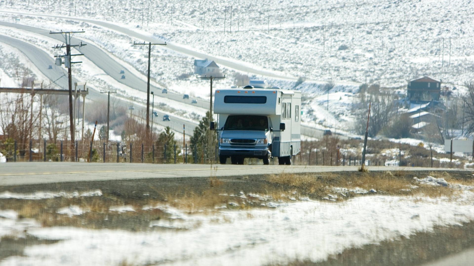 RV living tips are shown in this photo of an RV driving along the road in winter