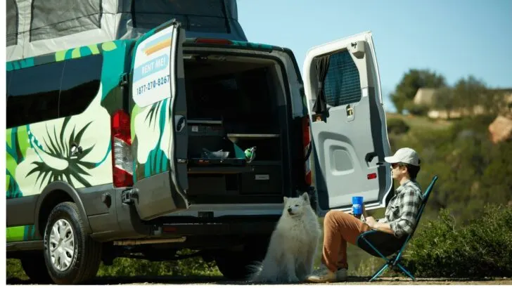 Photo of a man and his dog relaxing beside their camper van rented through Escape Campervans