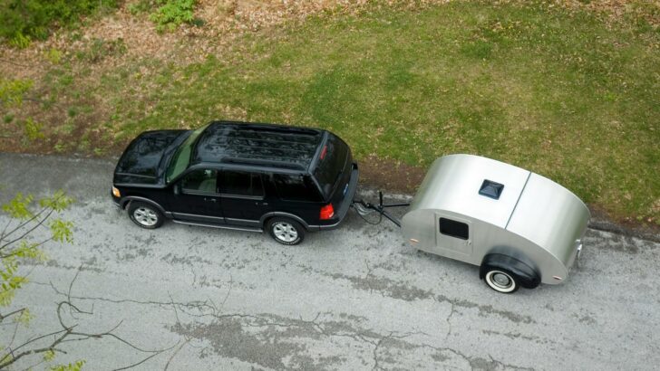 Aerial photo of an SUV towing a small teardrop travel trailer