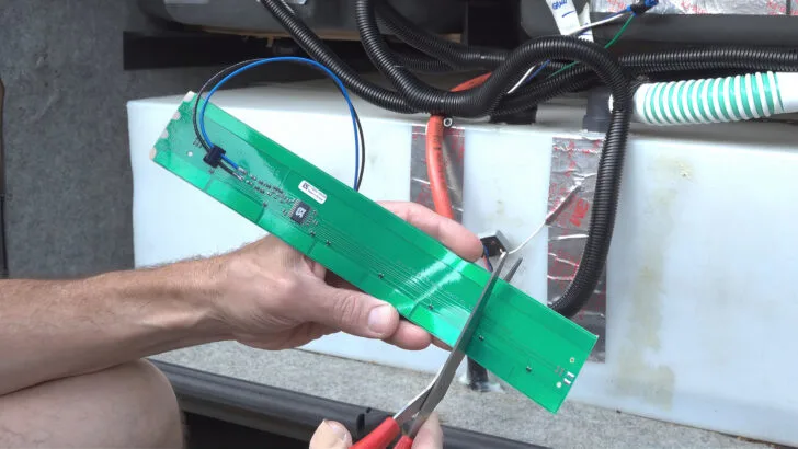 Using scissors to cut the SeeLevel tank sensor strip to the correct length