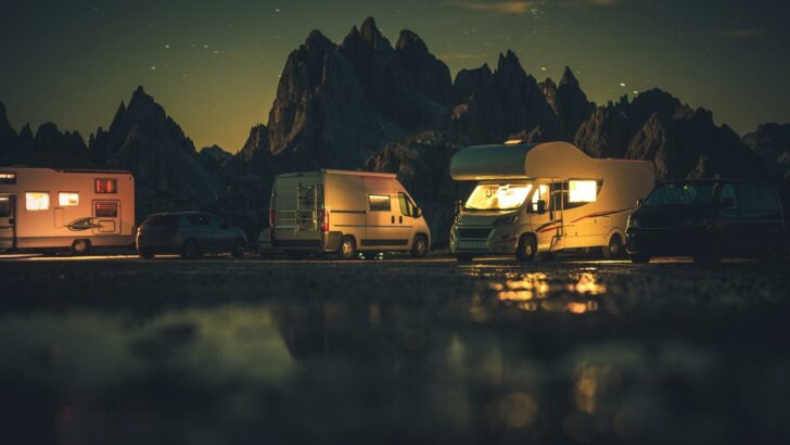 Several RVs parked by a body of water at night