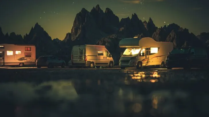 Several RVs parked by a body of water at night