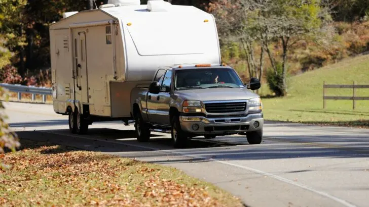 A fifth-wheel RV being transported by a truck
