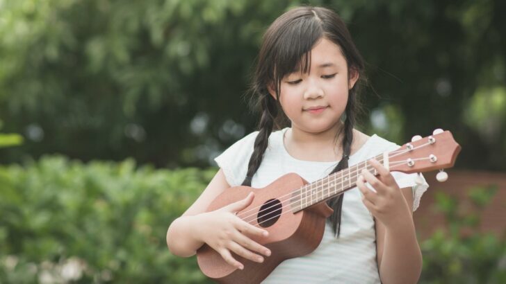 A little girl learning to play a ukelele