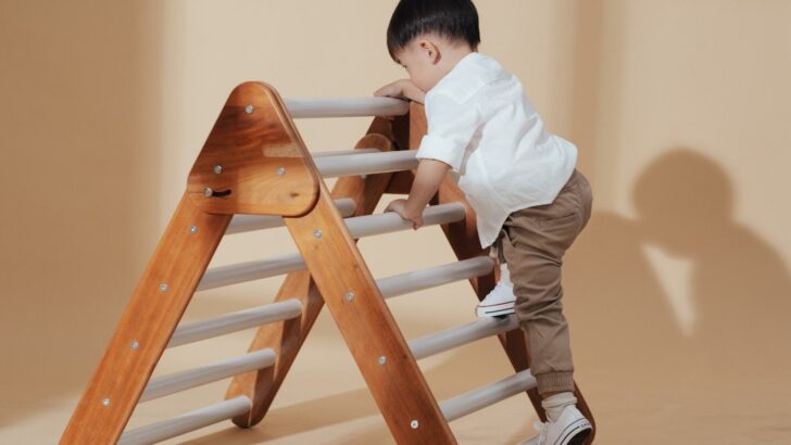 A toddler climbing a foldable wooden child's ladder