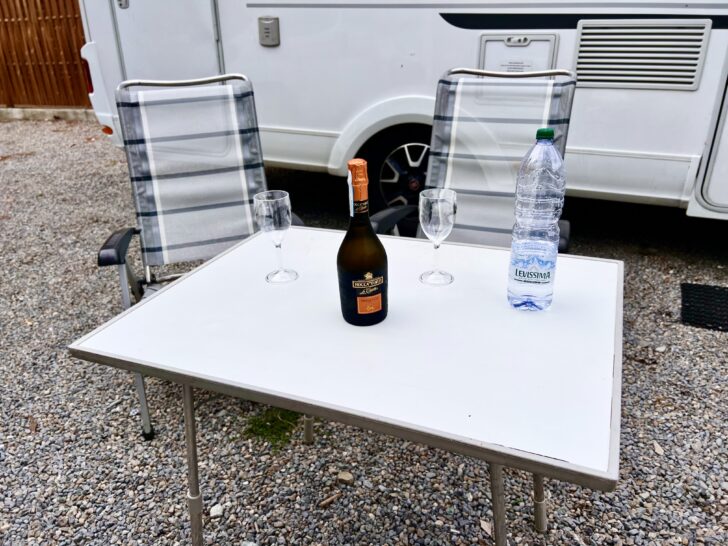 Folding camping table with a bottle or Prosecco on it.