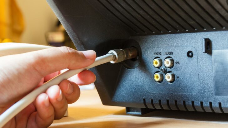 A person's hand attaching a coaxial cable to a TV