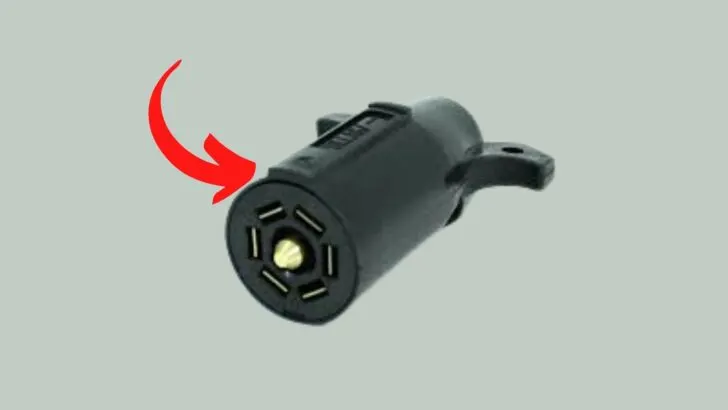 A 7-pin trailer plug with an arrow showing the top of the plug to orient the user to the various pins