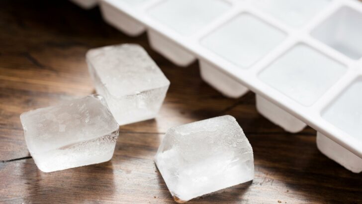 A few ice cubes beside an ice cube tray