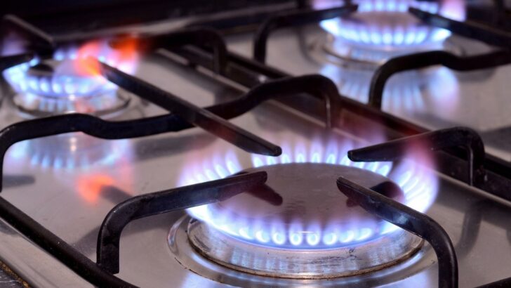 A propane stove with three burners lit