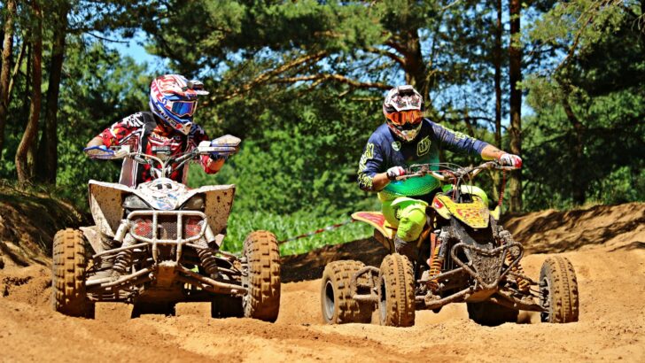 Two people riding ATVs on a trail