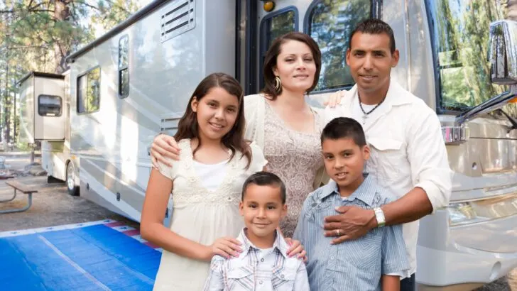 A family of 5 standing outside of their large RV