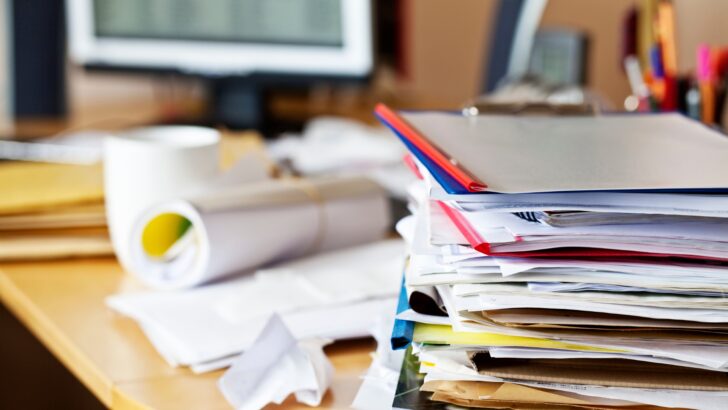 A messy desk containing files and papers