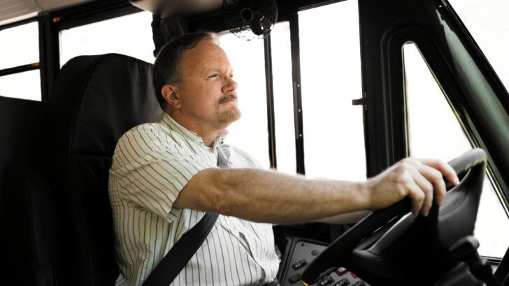 A man driving a bus with apparent concentration