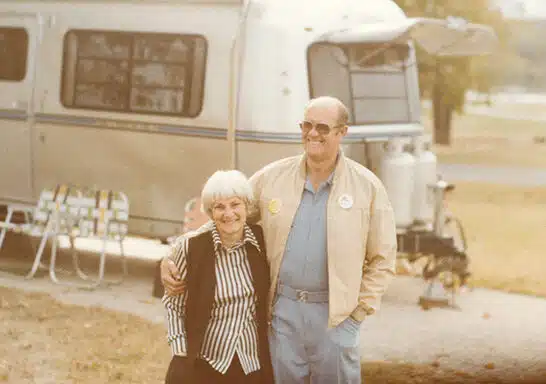 Kay and Joe Peterson, founders of the Escapees RV Club, standing in front of their RV.