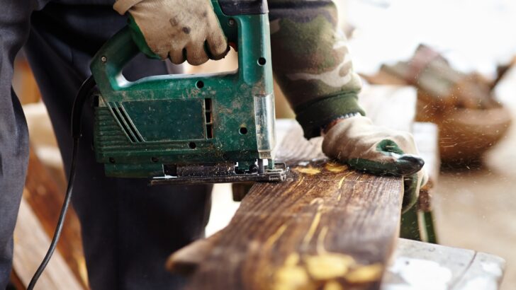 A person working with a power saw. Converting school buses into Skoolies often include a lot of custom woodwork