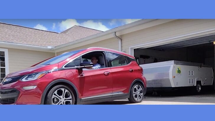 A Chevy Bolt electric vehicle towing an Aliner camper out of a garage