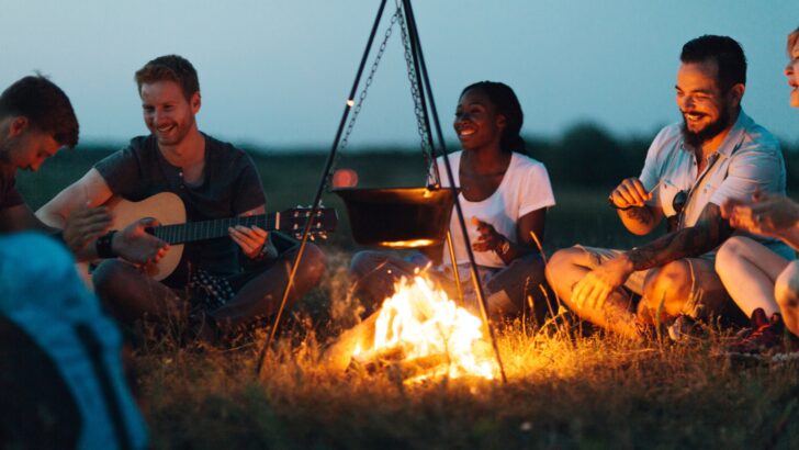 Adults singing around a campfire