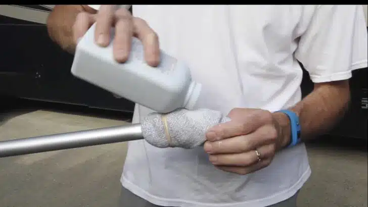 Peter sprinkling talcum powder onto an old sock secured to the end of an extension pole