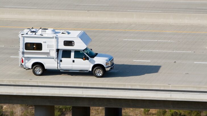 A truck camper on a truck traveling down the highway