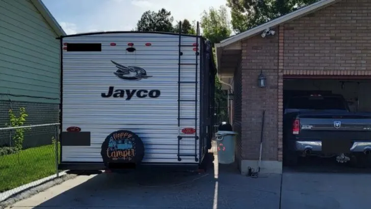 A travel trailer parked in a tight space between a garage and a fence is a perfect use for an electric trailer dolly
