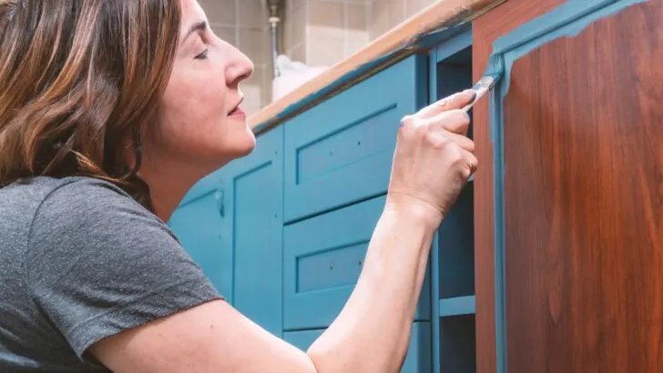 A woman painting lower cabinets with color