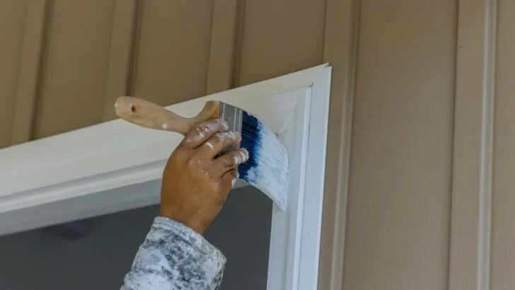 A person painting trim in white