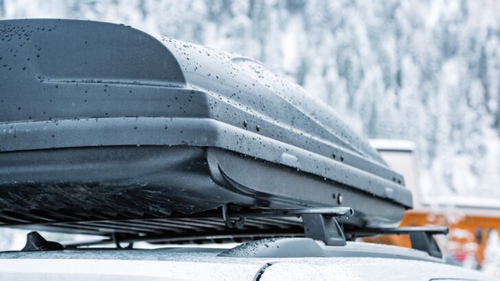 A wet rooftop cargo carrier with snow in the background