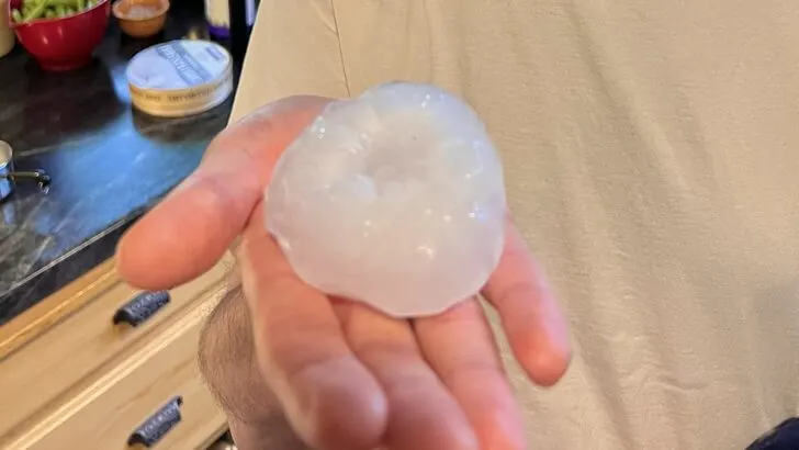 A huge piece of hail in the palm of a hand