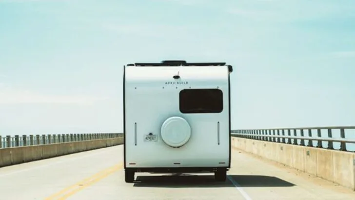 A view from behind the Coast Travel Trailer Model 1 as it travels down the road