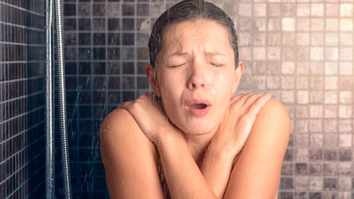 A woman getting hit with cold water in the shower