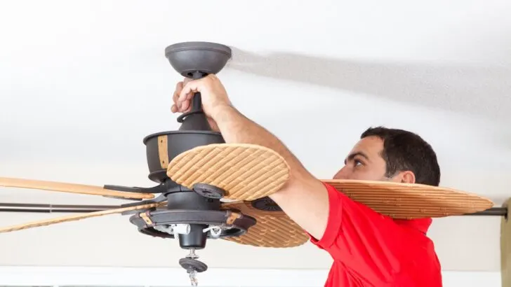 A man installing a large ceiling fan