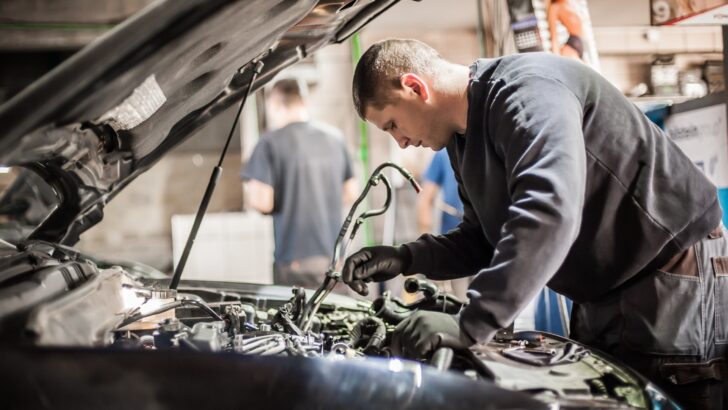 A man working under the hood of a vehicle