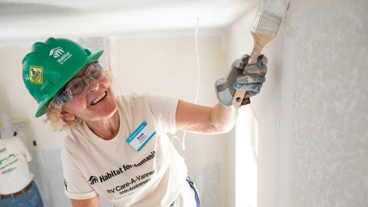 A member of RV Care-A-Vanners painting a Habitat for Humanity house