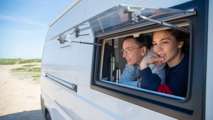 Two women looking out the open window of a small RV - debunking full time RV myths.