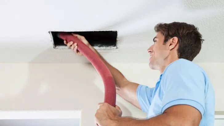A man vacuuming ceiling ducts
