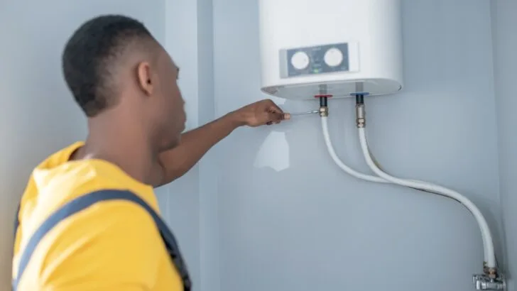 A man tightening the connections on a tankless water heater